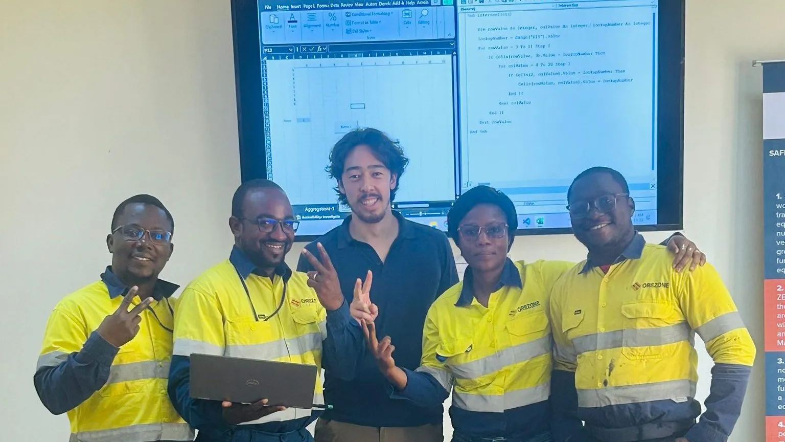 A client team in high-visibility workwear at a training session, in front of a screen.